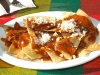 Tortilla chips with red mole and Oaxacan cheese