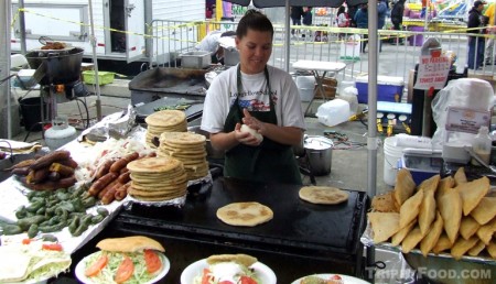 A woman at the San Fernando Festival makes pupusas by hand