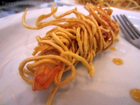 A perfectly cooked shrimp entwined in golden noodles