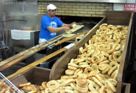 Dipping bagels into sesame seeds before baking