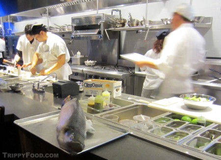 A paiche stands guard over the busy kitchen